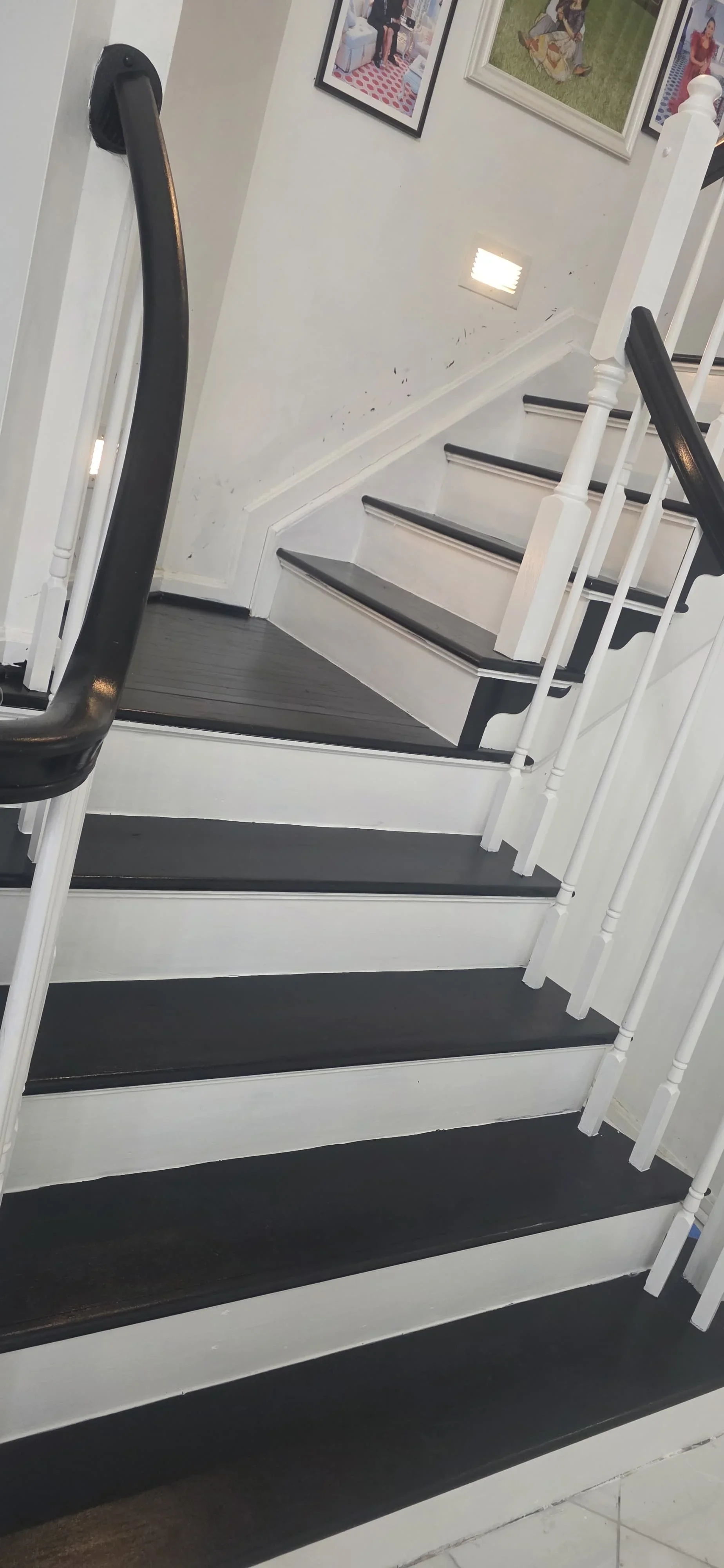 Modern staircase with white painted stringers, black treads, black runner, and white balusters