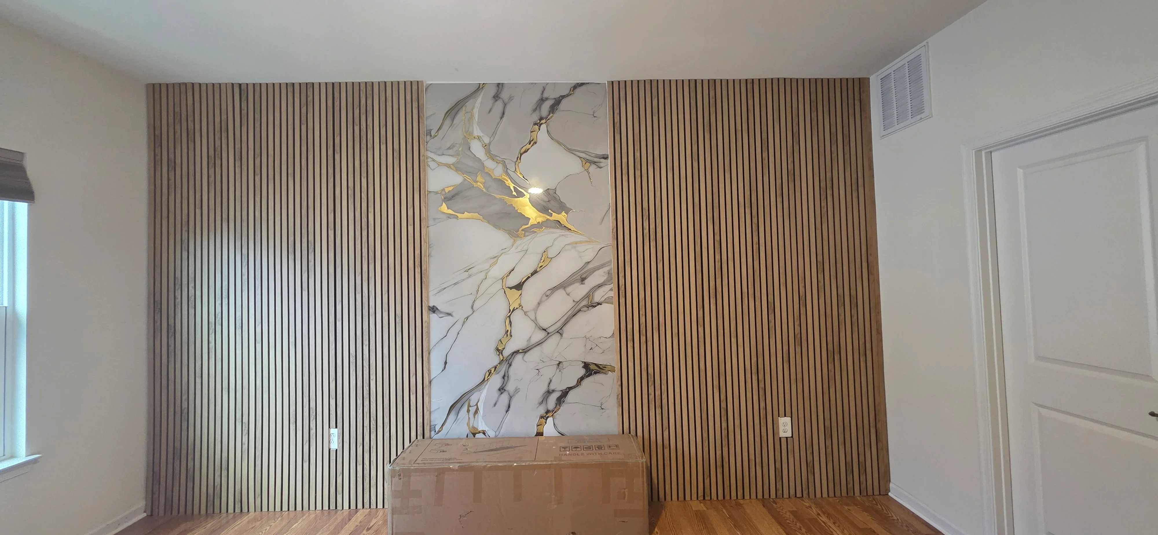 Vertical wood paneling with marble and gold accent panel installation in modern interior